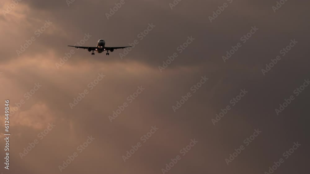 Jet plane flies at sunset. Flight arriving. Airliner approaching before landing in cloudy twilight sky Jet plane flies at sunset. Flight arriving. Airliner approaching before landing in cloudy twilight sky