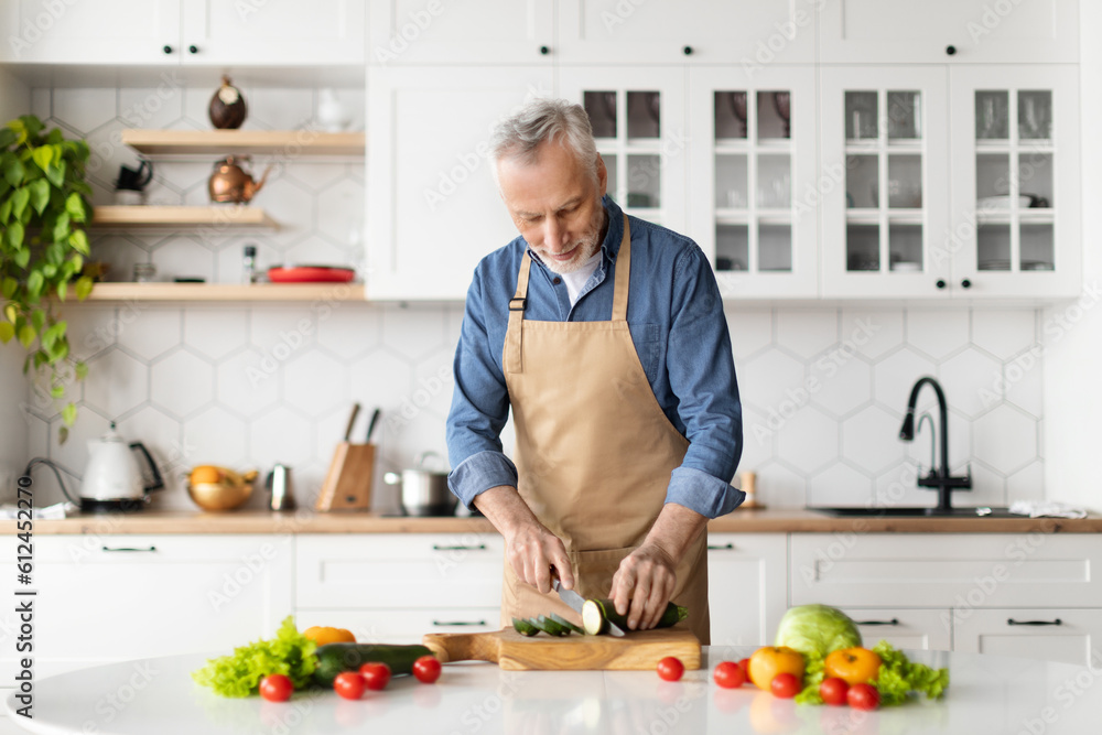 Happy senior man preparing healthy food in kitchen interior Happy senior man preparing healthy food in kitchen interior
