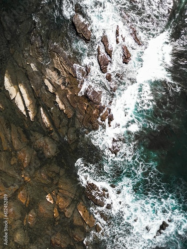 an aerial view of a rocky coast line with waves crashing against the cliffs