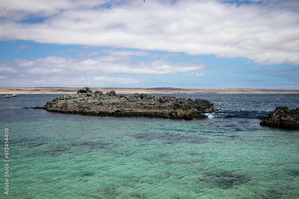 Closeup shot of a piece of rocky land in a blue ocean near the coastline