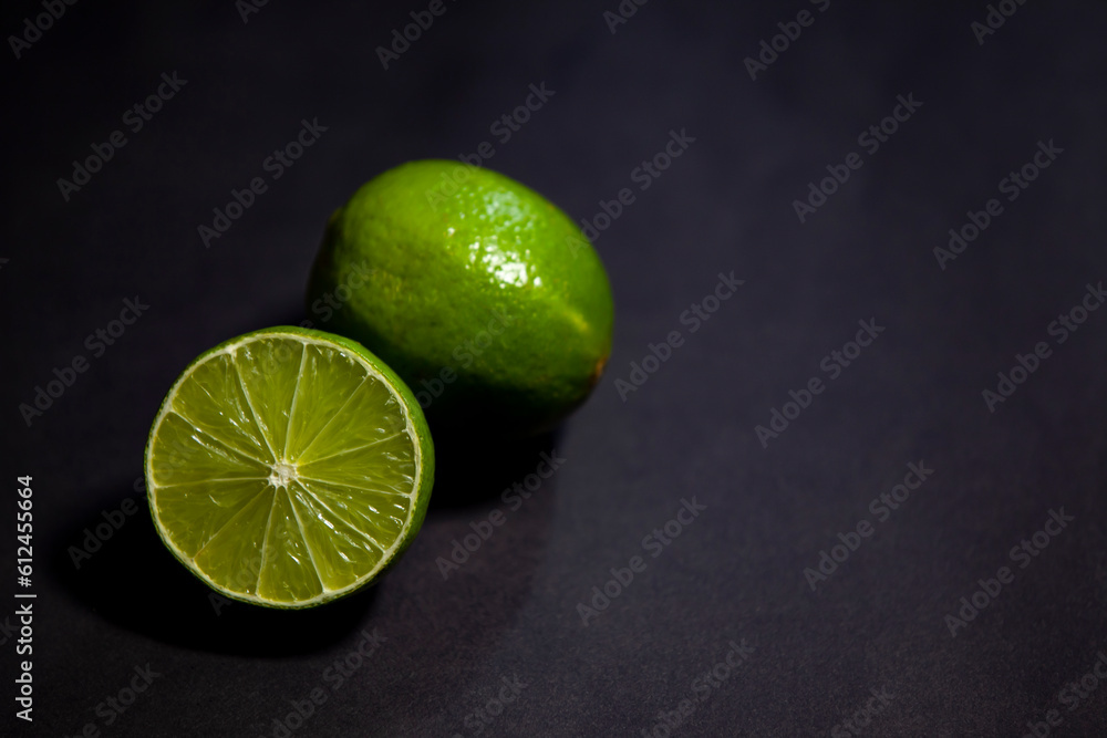 Limes against dark background, top view with copy space