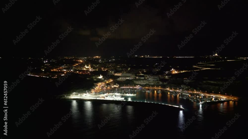Aerial shot of the buildings on the shore and the sea at night, Malta, Gozo Aerial shot of the buildings on the shore and the sea at night, Malta, Gozo