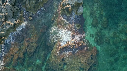 Aerial shot of the rocky mountains on the shore and a crystal clear sea, Malta, Imgiebah Bay photo