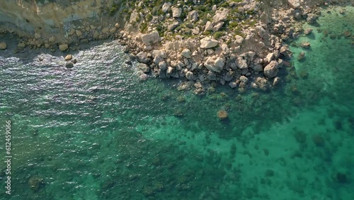 Aerial shot of the rocky mountains on the shore and a crystal clear sea, Malta, Imgiebah Bay photo