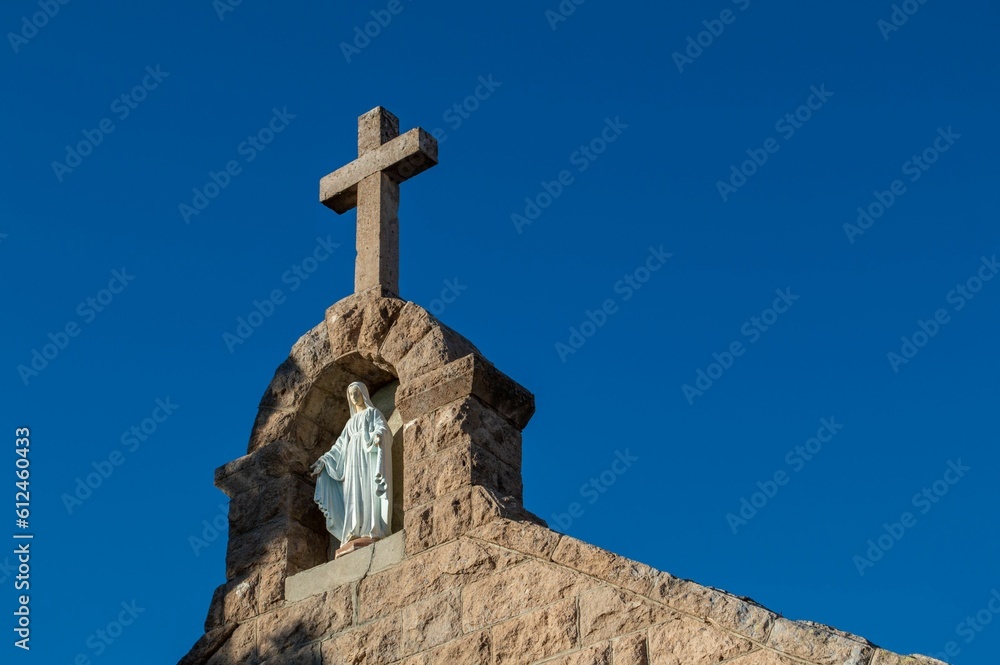 Low angle shot of Mother Mary statue and stone cross on the top of catholic church in Arizona