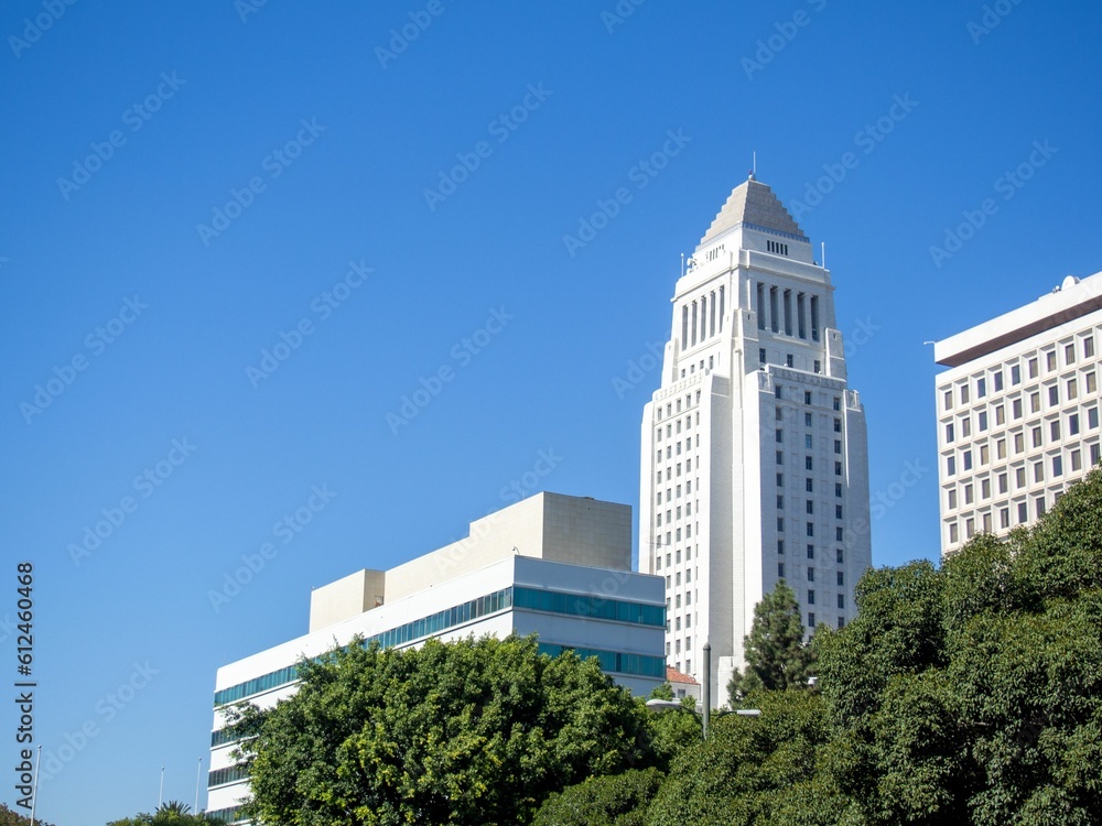 Low-angle shot of the city hall of Los Angeles with trees in front of it under blue sky