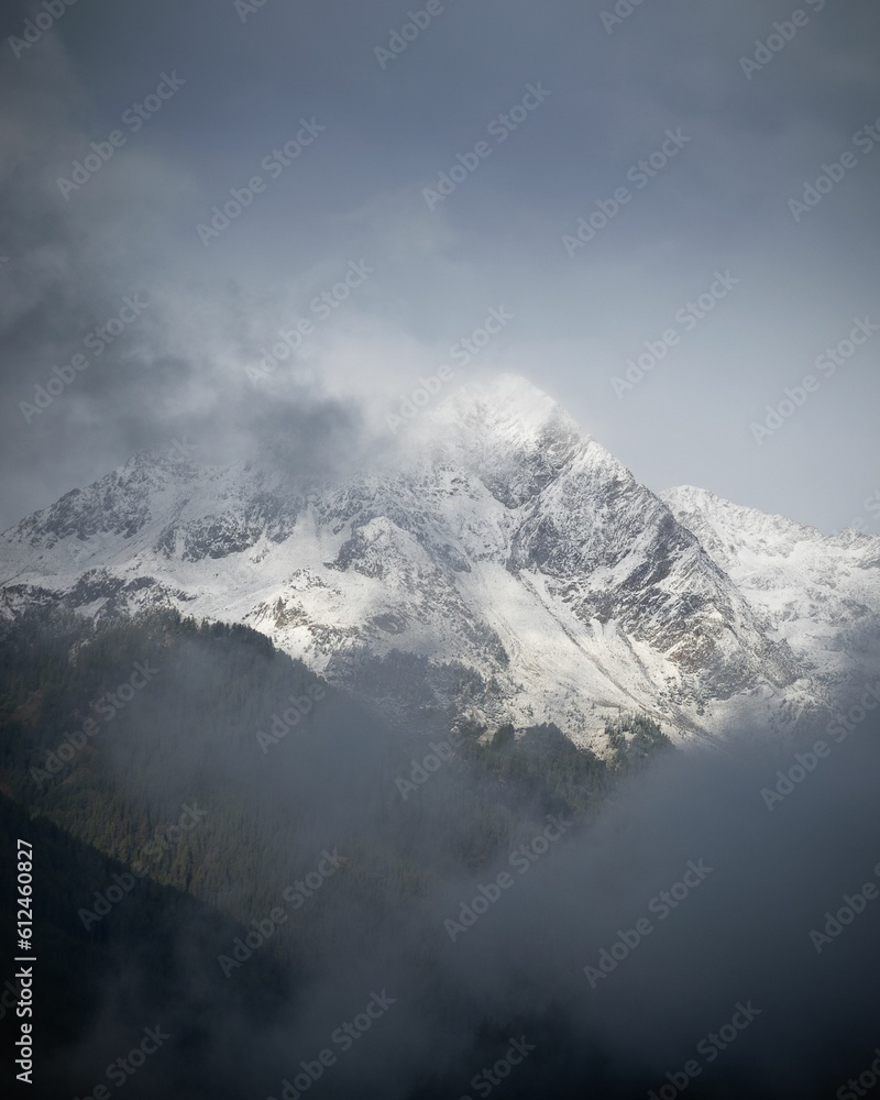 Vertical shot of a breathtaking snowy mountain covered in fog