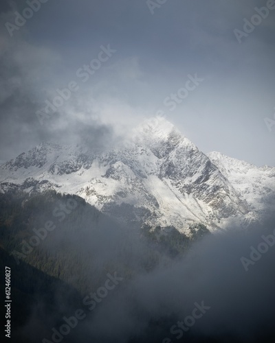 Vertical shot of a breathtaking snowy mountain covered in fog © Fabrizio Casale/Wirestock Creators