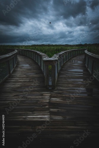 Vertical symmetrical view of a boardwalk slipt into different directions with a cloudy sky