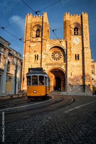 Vertical shot of the Lisbon Cathedral as a tram is passing in front of it