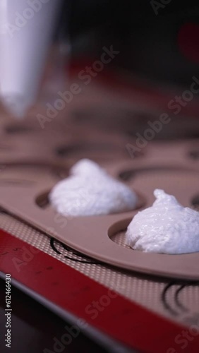 chef putting meringue from a piping bag to a mold. photo