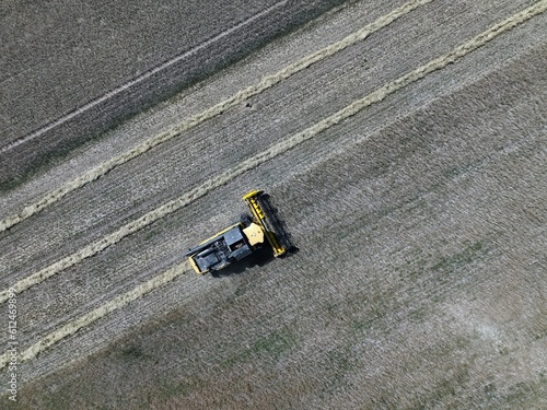 Aerial shot of a truck harvesting cereal from fields during the day