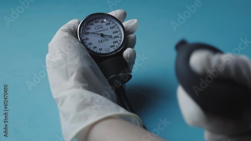 Closeup of a gloved hand checking blood pressure using an old blood pressure monitor