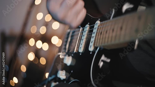 Closeup shot of a musician plugging an electric guitar and playing it in a studio