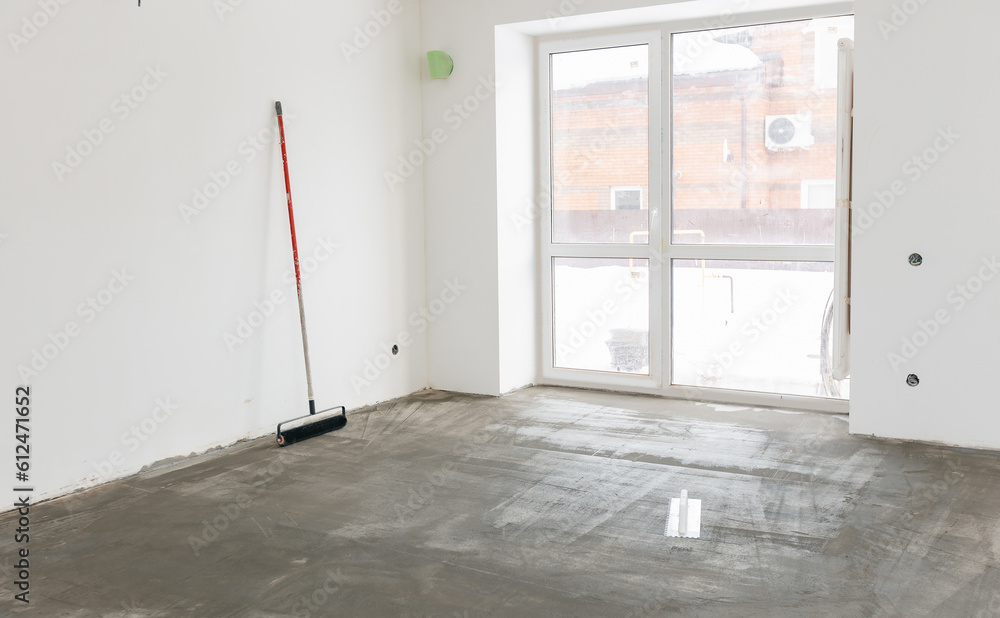 Foto de Worker use primer on concrete floor before laying tiles
