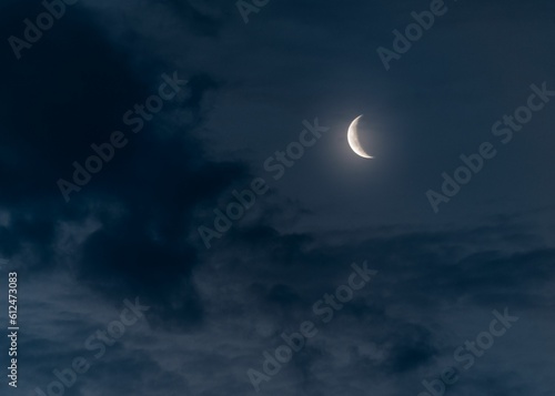 Beautiful shot of a half moon illuminating a dark blue cloudy sky