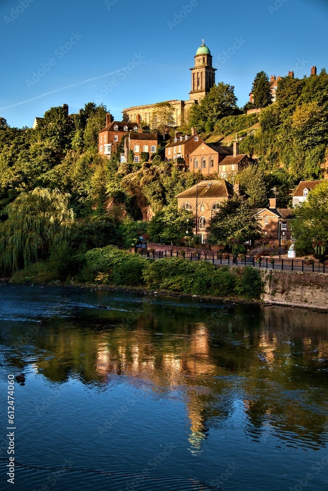 Vertical shot of Bridgnorth castle on a green hill, reflecting on a river in England, UK