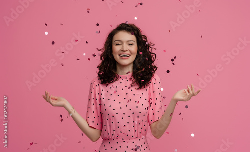 pretty young woman posing isolated on pink studio background with shiny confetti