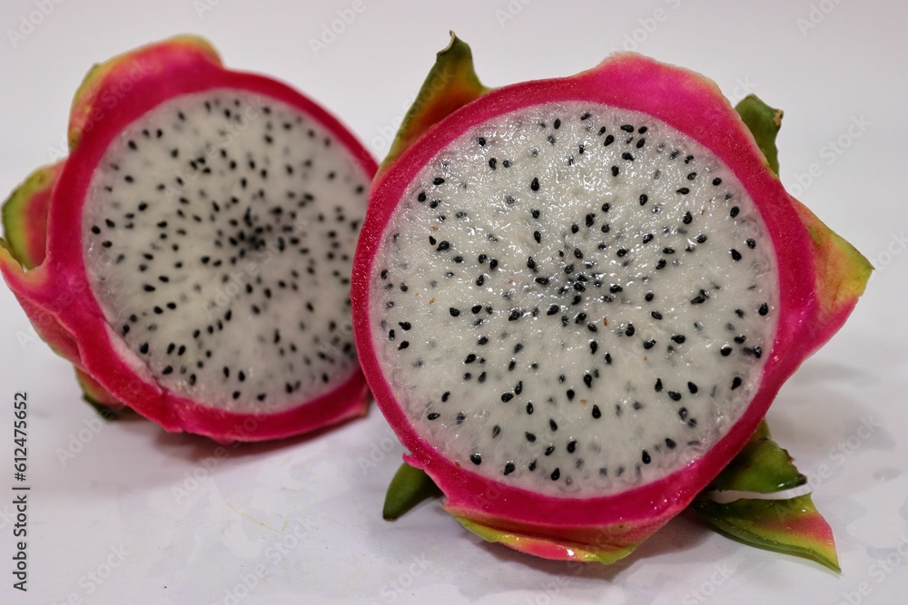 Closeup of a fresh dragonfruit cut in half on a white surface Closeup of a fresh dragonfruit cut in half on a white surface
