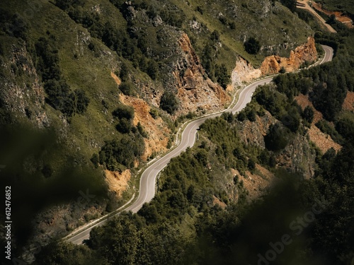 Aerial shot of a road going along the side of a green mountian