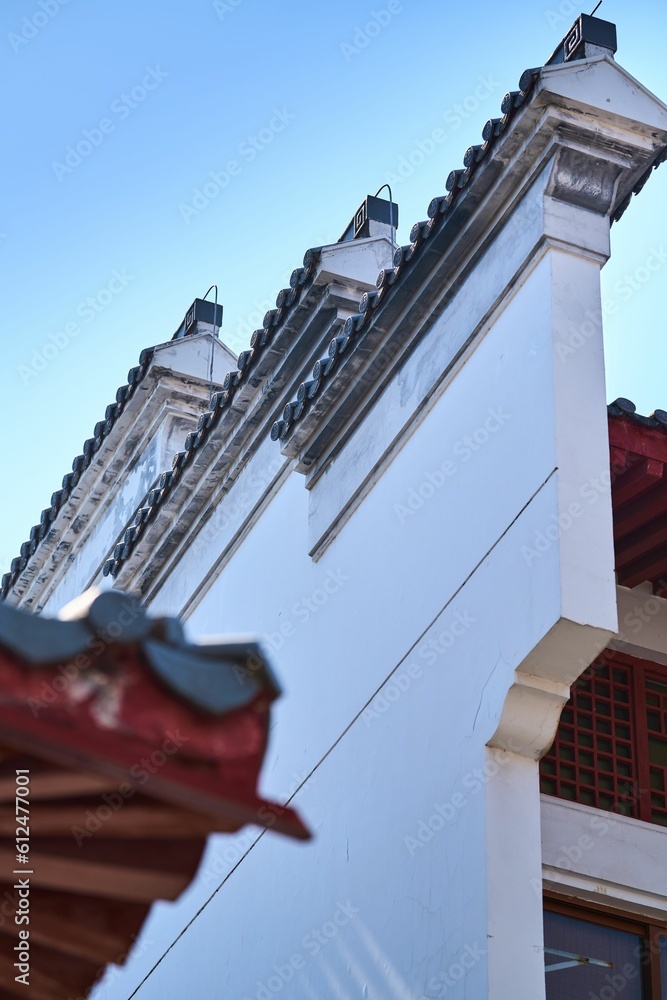Low angle vertical shot exterior of Chinese architecture facade with white walls under blue sky
