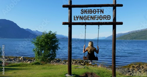 Back view of a young woman on the swing by Lyngenfjord in Northern Norway photo