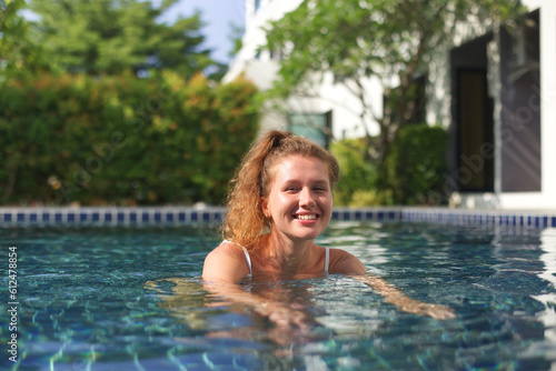 Young happy woman swim in swimming pool and smile, having fun 