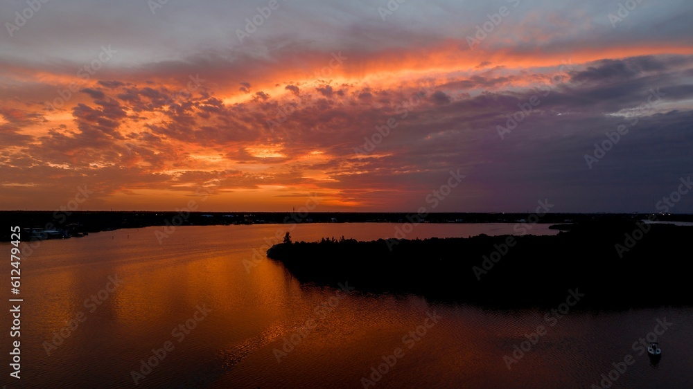 Beautiful view of a calm sea during a lovely sunset with an orange glow around dark blue clouds Beautiful view of a calm sea during a lovely sunset with an orange glow around dark blue clouds