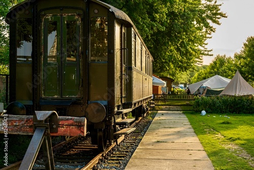 Vintage train wagon on metal railway in the garden with grass and trees on a sunny day