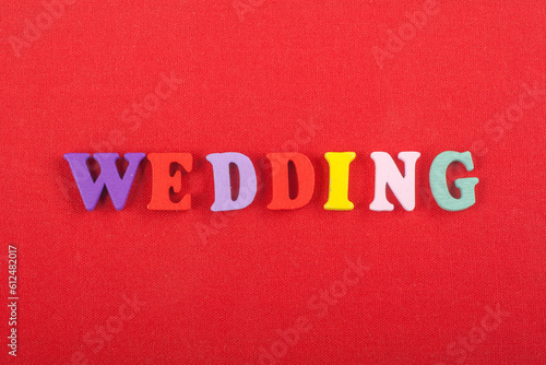 WEDDING word on red background composed from colorful abc alphabet block wooden letters, copy space for ad text. Learning english concept.