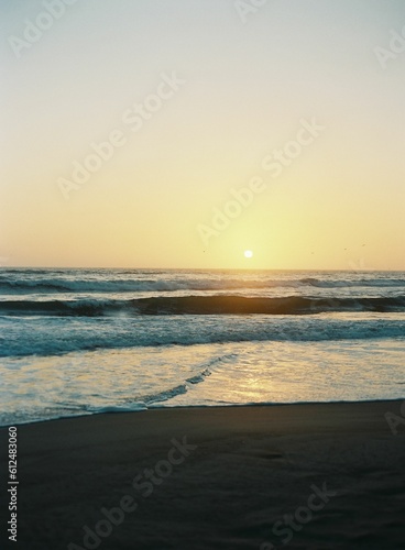 Beautiful shot of waves washing up the sandy beach at sunset