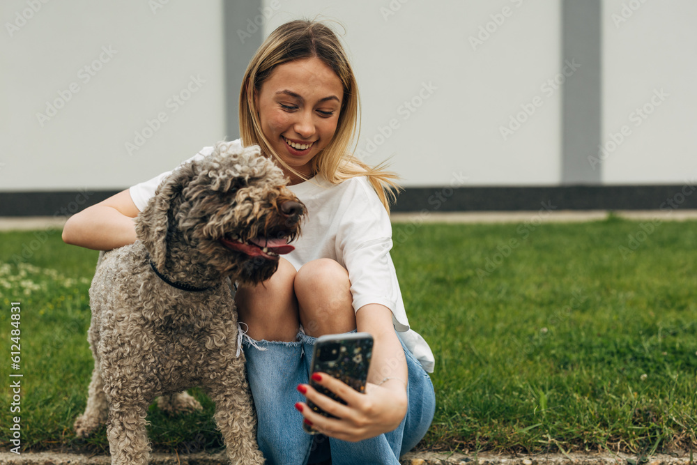 Φωτογραφία Teenage girl is taking a selfie with her adorable happy dog outside