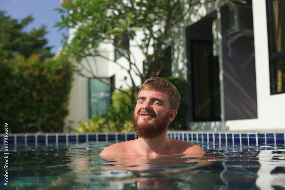 Young happy man swim in swimming pool and smile, having fun, enjoy summer sunny weather, vacation 