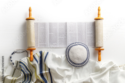 Torah scroll with prayer shawl tallit and kippah on a light background photo