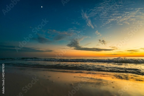 Image of a sunset in the yellow sky from the sea. © Jay_30a/Wirestock Creators