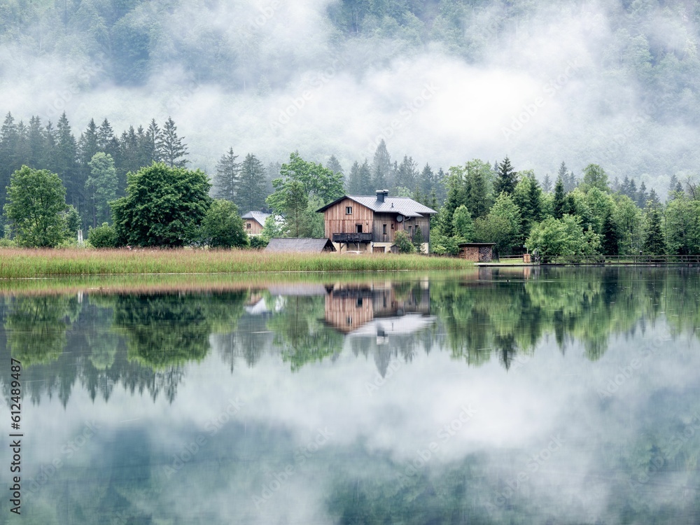 Beautiful shot of a wooden house onshore of lake Alm reflecting the environment