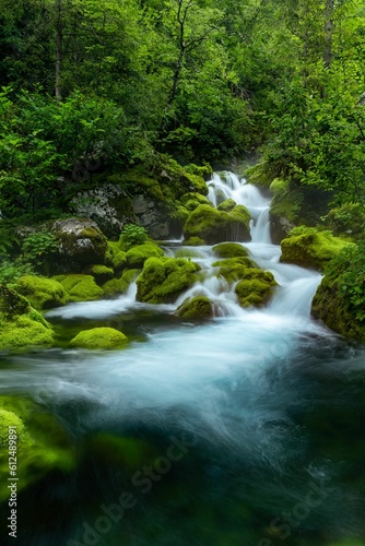 Landscape waterfall stream on river with mossy rocks and trees in Slovenia