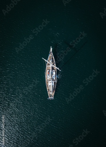 Vertical shot of a white yacht sailing in the sea on a sunny day