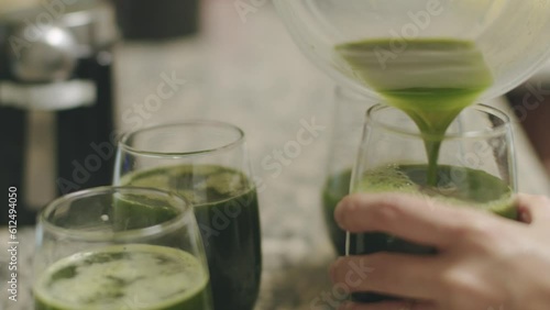 Closeup footage of a hand pouring squeezed pennywort juice into glasses photo