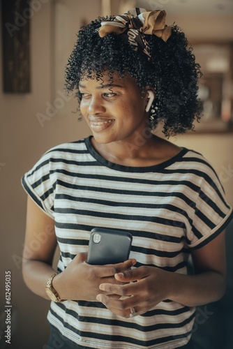 Vertical shot of a young female talking to phone with wireless earbuds on
