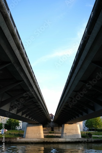Low angle shot of the two bridges over the calm waters of a river against the blue sunny sky © Burgie/Wirestock Creators