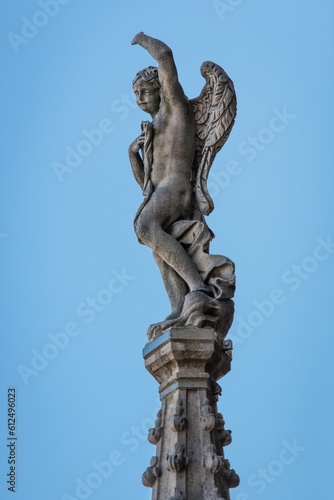 Vertical shot of the statue of angel on roof of Milan Cathedral  Italy on a blue sky background