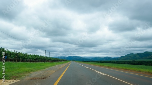 Empty, straight asphalt road at a countryside under a cloudy sky