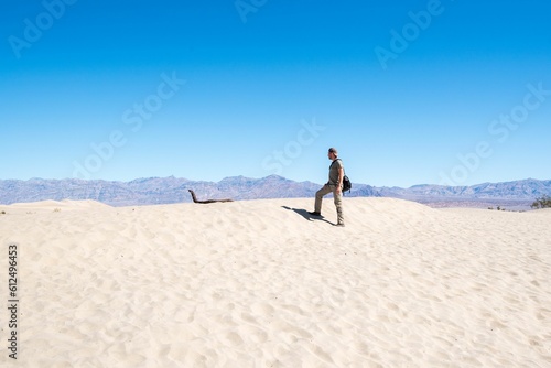 Male traveler walking on sand in the desert under the blue sky on a sunny summer day