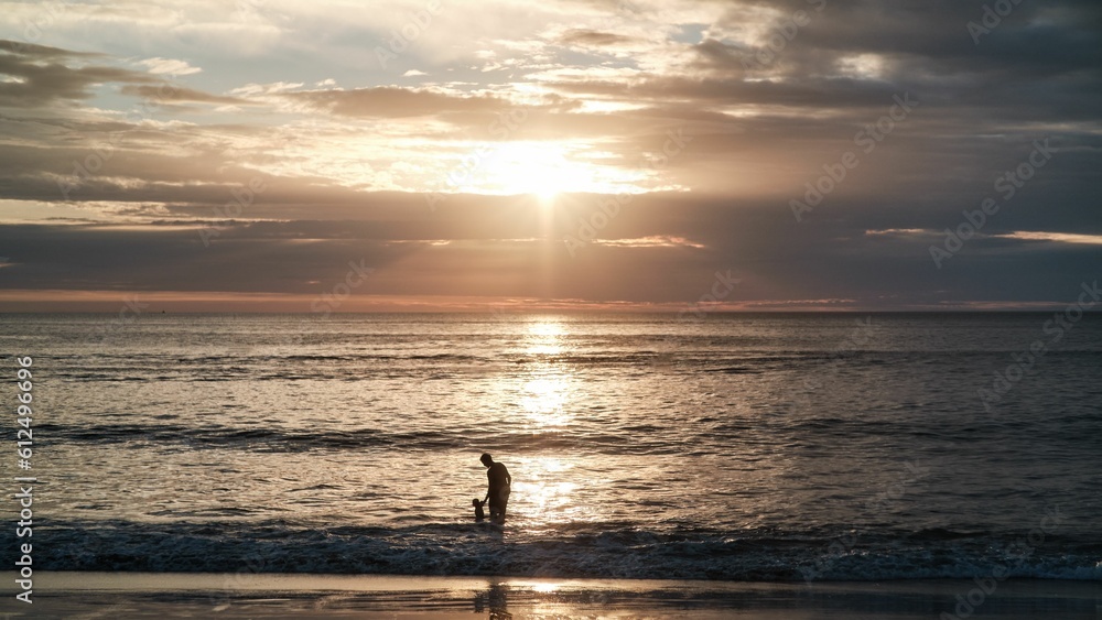 Silhouette of a father and a son on a seashore at sunset in Tamarindo, Costa Rica