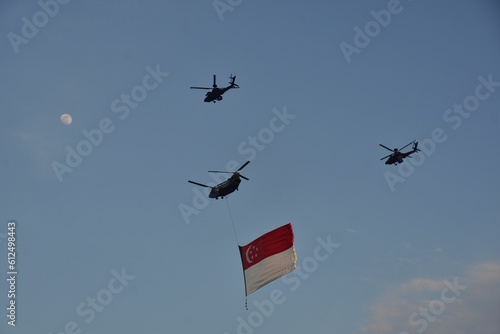 Helicopters flying in the blue sky while holding the Singapore flag photo