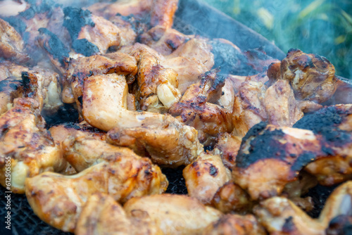 chicken drumsticks are grilled on a barbecue grill in the evening.