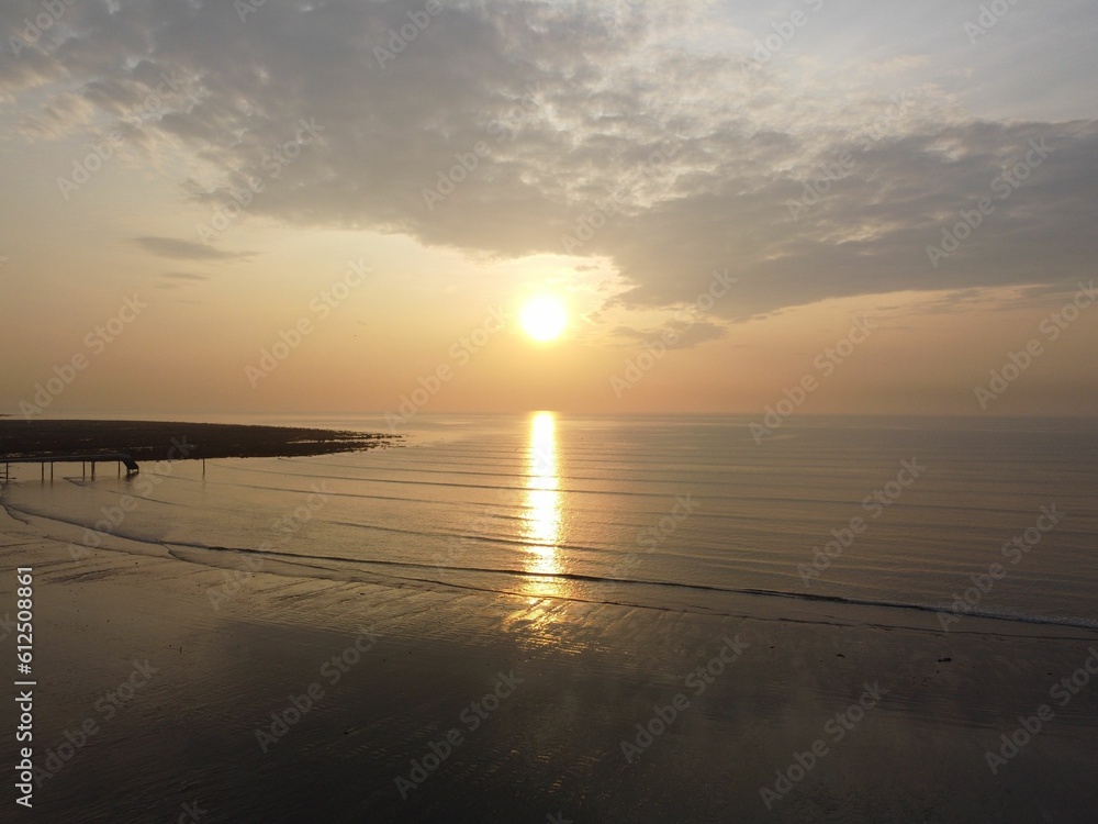 Fototapeta premium Beautiful view of the sea under the cloudy sky during orange sunset