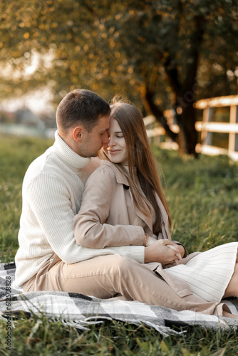 Mothers day. Stylish marriage pregnant couple waiting for baby. Man hugs and touches woman belly outdoors on plaid on grass. Family day. Pregnancy, parenthood, motherhood, love, family concept. © Andriy Medvediuk