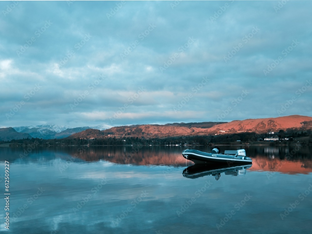 Obraz premium Boat in Ullswater lake in England with hills in the background against a clouded sky